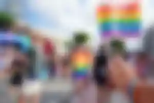 Regenbogenfahne bei einer Pride-Veranstaltung in einer belebten Urlaubsdestination mit zahlreichen Besucherinnen und Besuchern