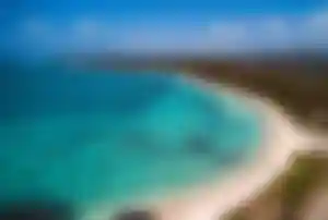Weißer Sandstrand von Belle Mare mit türkisblauem Wasser und sanft geschwungenem Küstenverlauf.