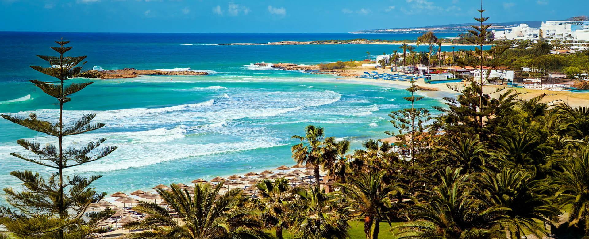 Zypern Hotels an der Küste – Strand, Meer und Hotelanlagen im Überblick Küstenlandschaft auf Zypern mit türkisfarbenem Meer, Sandstrand, Palmen und Hotels entlang der Mittelmeerküste