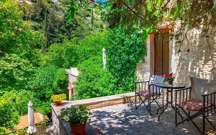 Gemütliche Terrasse mit Tisch und Stühlen, umgeben von üppigem Grün in Myli auf Kreta.