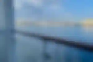 Balkonausblick auf der MS Europa mit Blick auf die Küste Aussicht von der Veranda einer Suite auf der MS Europa auf Hafen und Küstenstadt bei ruhiger See