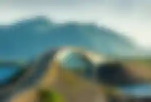 Geschwungene Brücke der Atlantikstraße in Norwegen mit Bergen im Hintergrund und Blick auf das Meer