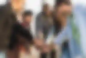 Gruppe von Reisenden steht im Kreis und legt gemeinsam die Hände übereinander während einer Gruppenreise