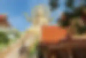 Große goldene Buddha-Statue am Wat Phra Yai auf Koh Samui mit Treppenaufgang und Tempelanlage