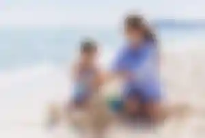 Erwachsene Person und Kind bauen Sandburgen an einem Sandstrand am Meer während eines Sommerurlaubs in Italien.