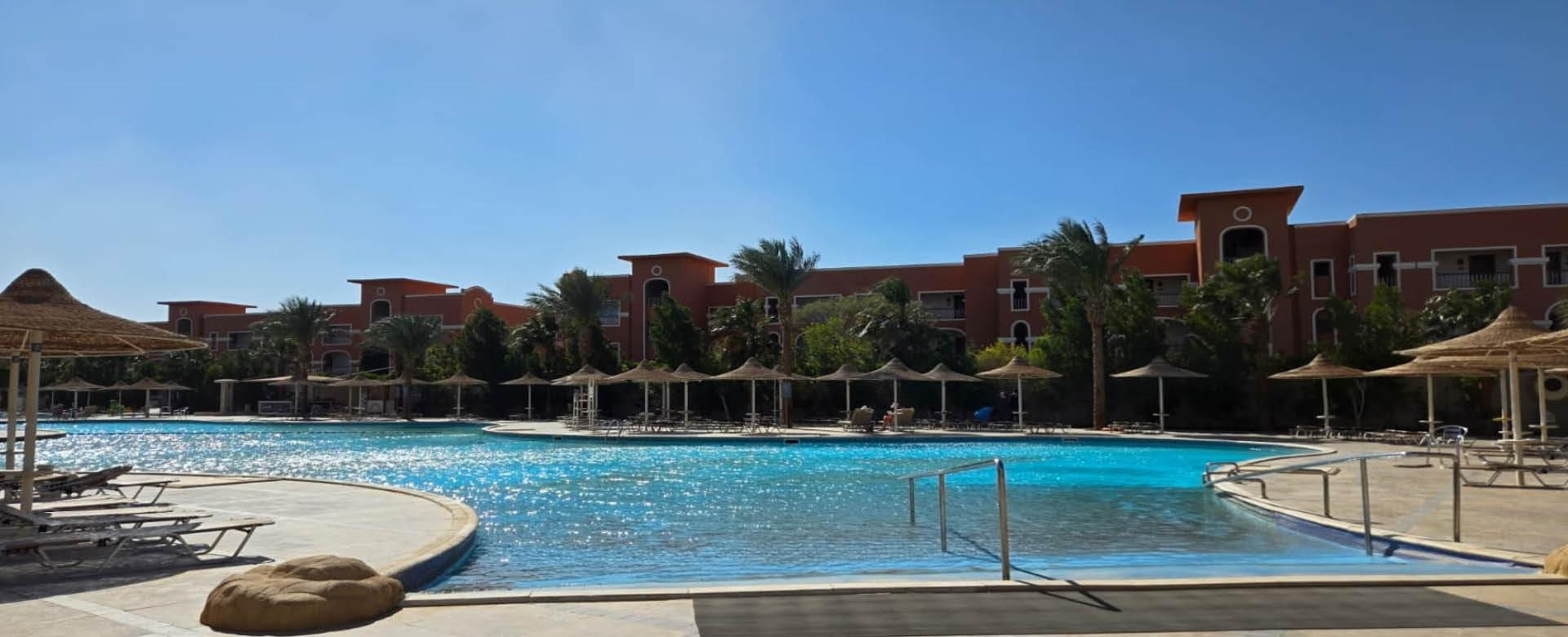 Hotelpool in Hurghada – beste Hotels Hurghada mit All Inclusive Großer Poolbereich eines Hotels in Hurghada mit Sonnenschirmen, Palmen und Hotelgebäuden im Hintergrund bei klarem Himmel