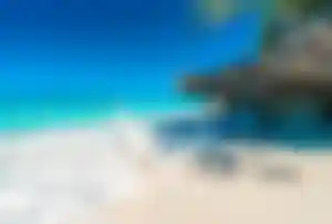 Tropischer Strand auf Sansibar mit Felsen, weißem Sand und Wellen im türkisfarbenen Meer