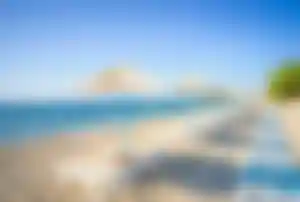 Sandstrand auf Kos mit Sonnenschirmen, Liegen und kristallklarem Meer an der griechischen Küste