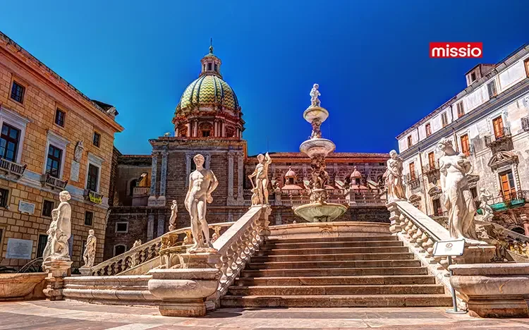 Piazza Pretoria in Palermo mit monumentaler Marmortreppe, zahlreichen Statuen und der Kuppel der Kirche Santa Caterina unter blauem Himmel