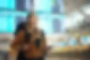 Backpacker mit Rucksack steht in einem Flughafen vor einer Abflugtafel