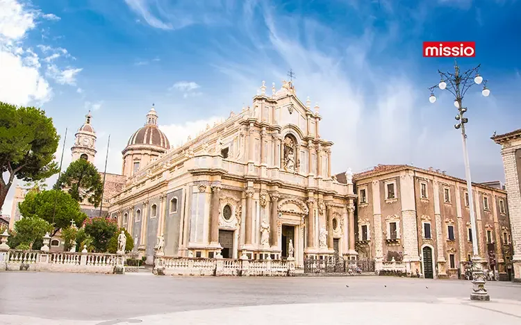Barocke Fassade der Kathedrale von Catania auf einem offenen Platz mit historischen Gebäuden und blau weißem Himmel