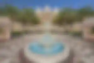 Eindrucksvoller Eingangsbereich des Raffles The Palm Dubai mit Springbrunnen, Palmen und luxuriöser Architektur