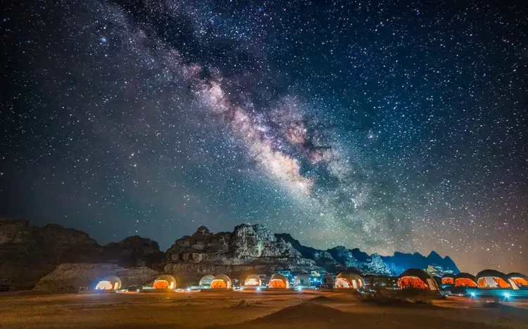 Sternenklare Nacht mit Milchstraße über Beduinenzelten in der Wadi-Rum-Wüste.