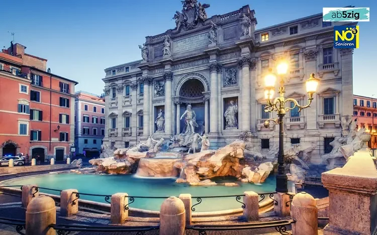 Trevi-Brunnen in Rom bei Dämmerung, beleuchtete Barockfassade und türkisfarbenes Wasser im Vordergrund.