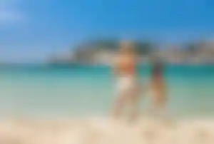 Mutter und Tochter stehen Hand in Hand am Meer in Mallorca