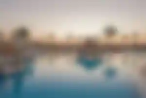Große Poollandschaft im SUNRISE Royal Makadi Resort in Hurghada mit Palmen, Liegen und Brücke über dem Wasser
