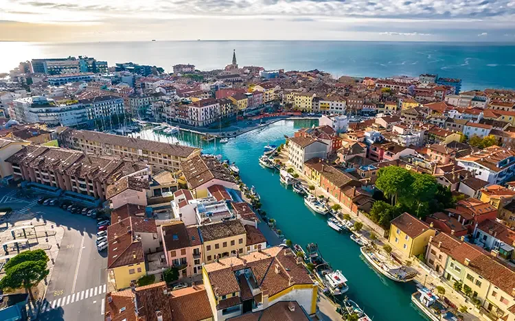 Luftaufnahme von Grado in Italien mit Hafen, engen Kanälen, bunten Häusern und Blick auf die Adria