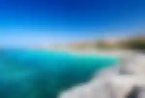 Küstenabschnitt mit Strand, klarer See und Urlaubsanlagen auf Teneriffa.