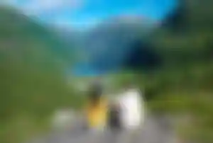 Blick auf den Geirangerfjord mit Dorf, Fjordwasser und hohen Bergen aus erhöhter Perspektive
