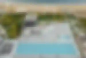 Luftaufnahme der modernen Hotelanlage Paloma Finesse Side mit großem Pool, vielen Sonnenschirmen, direktem Zugang zum Sandstrand und dem Meer an der türkischen Riviera.