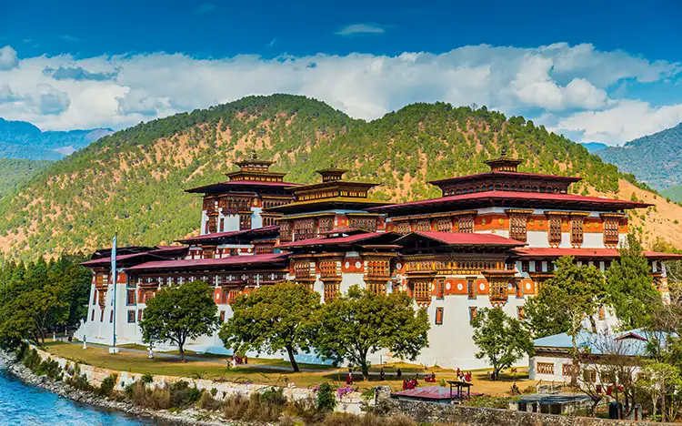 Majestätischer Punakha Dzong am Ufer des Mo Chhu Flusses umgeben von grünen Hügeln in Bhutan