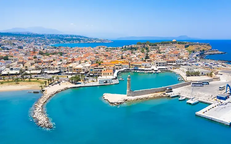 Luftaufnahme des venezianischen Hafens von Rethymnon auf Kreta mit türkisblauem Wasser und historischen Gebäuden.