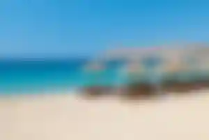 Sonnenliegen und Sonnenschirme am Elia Beach auf Mykonos mit türkisblauem Meer und Sandstrand