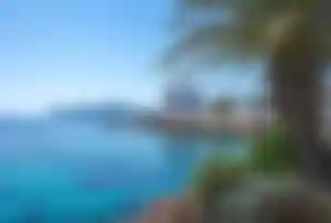Küste bei Cala Millor mit klarem Wasser, Felsenlandschaft und Hotels im Hintergrund auf Mallorca