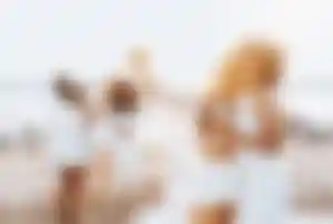 Gruppe von Reisenden genießt gemeinsam einen Sommerabend am Strand mit Blick auf das Meer