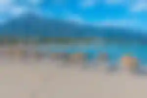 Sandstrand an der Costa del Sol mit Sonnenschirmen, Liegen und Bergkulisse im Hintergrund