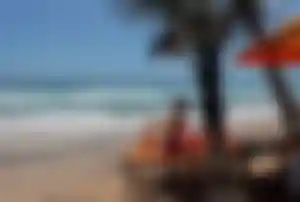 Person entspannt auf einer Liege unter Palmen an einem Sandstrand in Sri Lanka