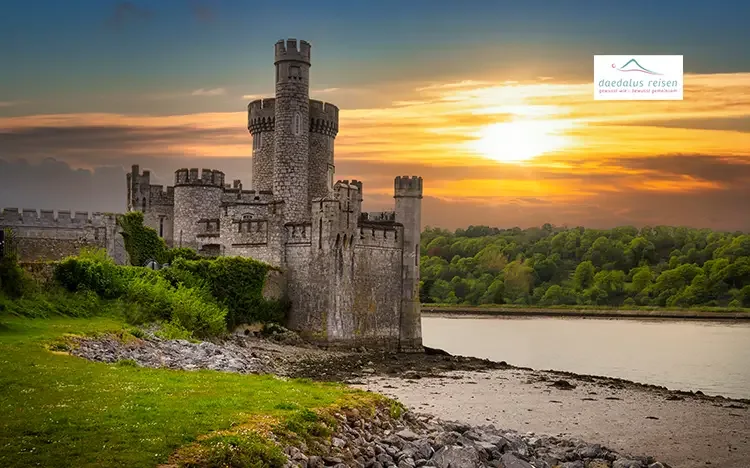 Historisches Schloss bei Cork am Flussufer während des Sonnenuntergangs