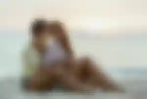 Zwei Frauen sitzen gemeinsam am Strand und genießen den Sonnenuntergang am Meer