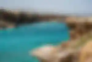 Kleine Bucht mit türkisfarbenem Wasser, zerklüfteter Felsküste und Bergen im Hintergrund auf Kreta