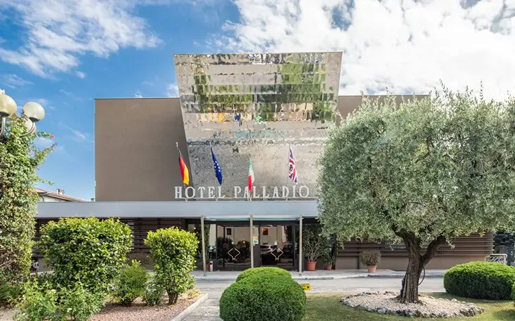 Außenansicht des Hotel Palladio mit moderner Fassade und Landesflaggen vor dem Eingang.