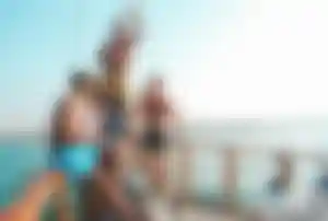 Gruppe feiert Partyurlaub auf einem Boot mit Blick aufs Meer und entspannter Sommerstimmung
