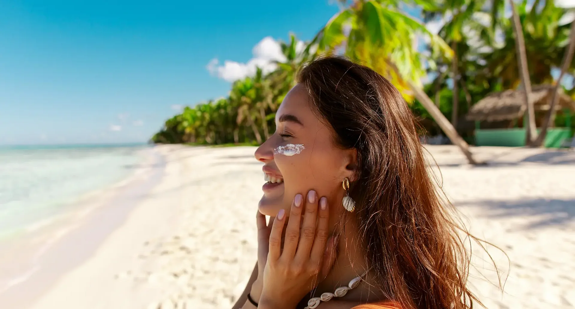 Person steht an einem weißen Sandstrand mit Palmen und Meer im Hintergrund, typisches Motiv für Low Budget Reiseziele mit Sonne und Strand
