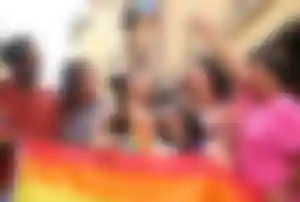 Gruppe von Menschen mit Regenbogenfahne in einer europäischen Altstadt während einer LGBTQ Veranstaltung