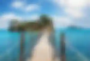 Holzsteg über türkisfarbenes Wasser zur kleinen Insel bei Zakynthos